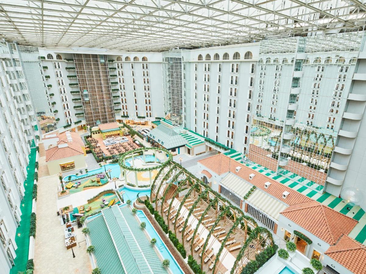 Grand Nikko Tokyo Bay Maihama Hotel Urayasu Exterior foto The photo shows a large indoor space, likely a hotel or resort atrium. The area features multiple levels of buildings surrounding a central courtyard. This courtyard includes various amenities such as pools, landscaped gardens, and recreational areas