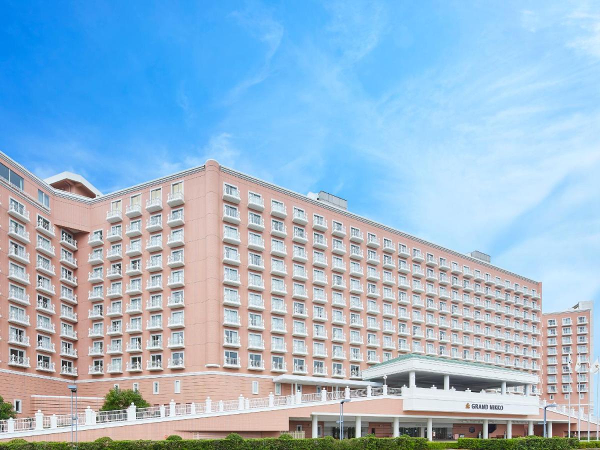 Grand Nikko Tokyo Bay Maihama Hotel Urayasu Exterior foto The photo depicts a large hotel building featuring a contemporary architectural design. The structure is predominantly pink, with multiple floors and numerous windows. There is a covered entrance at the front, and the setting appears to be well-maint