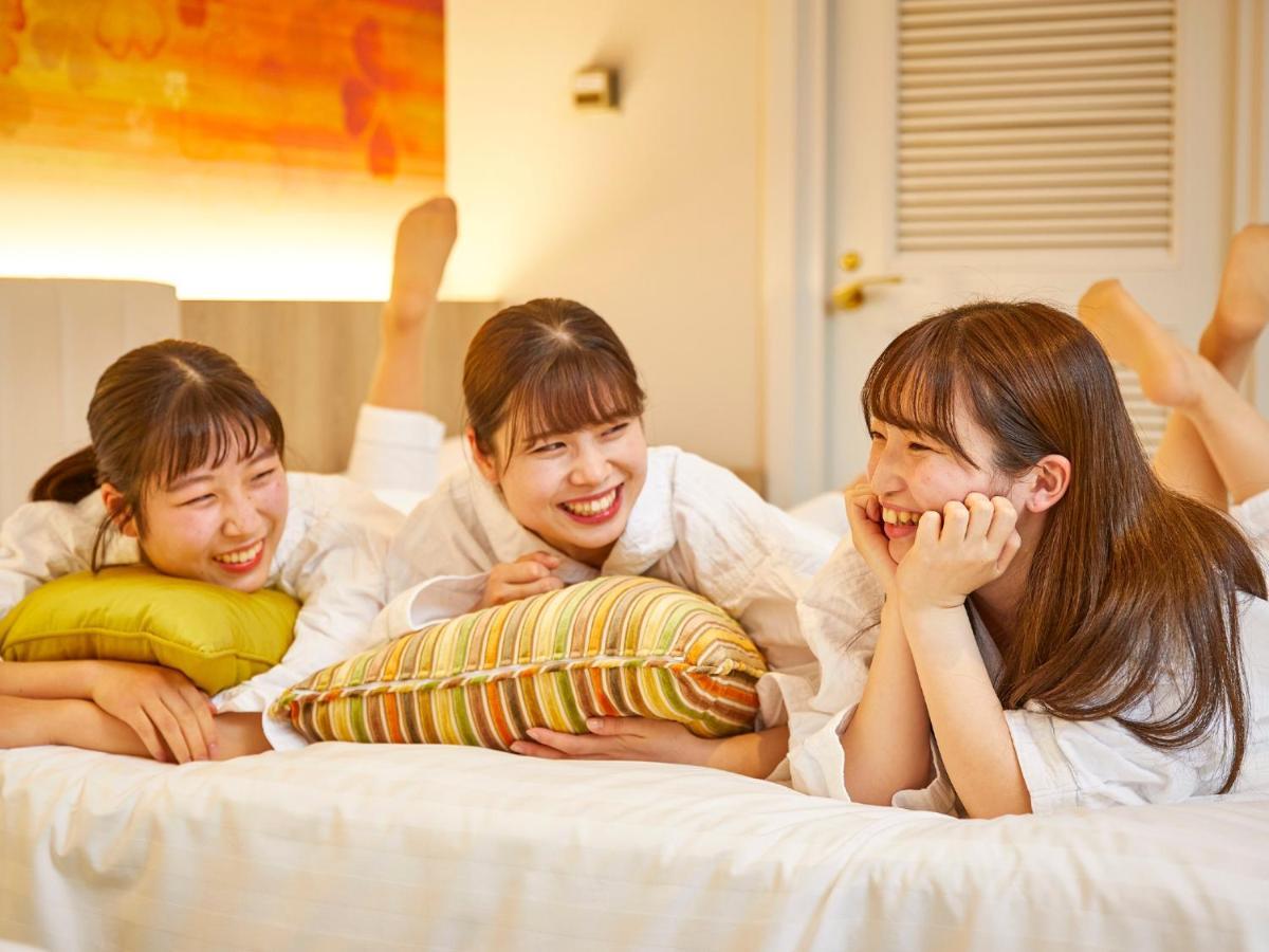 Grand Nikko Tokyo Bay Maihama Hotel Urayasu Exterior foto The photo shows three young women lounging together in a cozy indoor setting. They are dressed in white robes and appear to be relaxed and enjoying each other's company. The women are lying on a bed, with two of them resting on their arms and the thi
