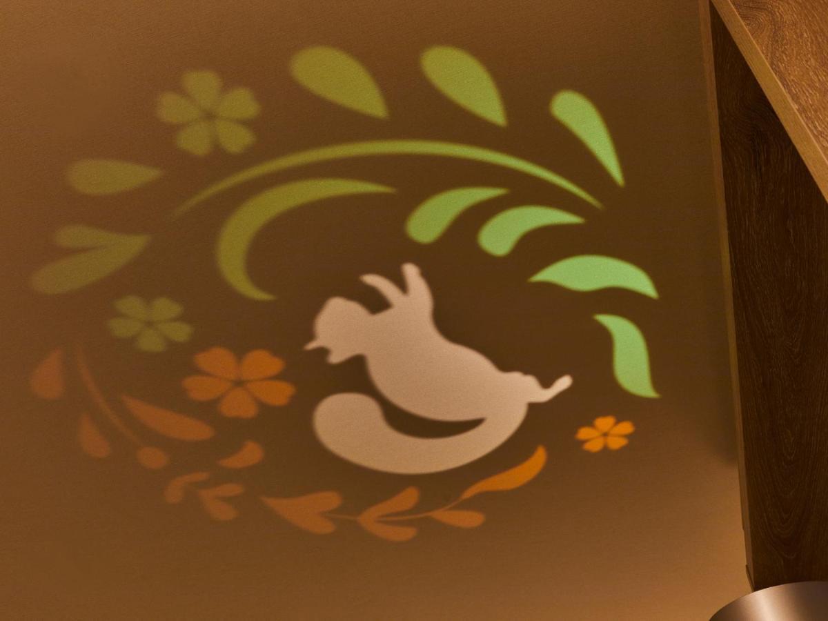 Grand Nikko Tokyo Bay Maihama Hotel Urayasu Exterior foto The photo shows a colorful projection on a surface that includes a playful illustration. The design features a white silhouette of a squirrel in a lively pose, surrounded by decorative elements like green leaves and flowers in shades of orange and ye