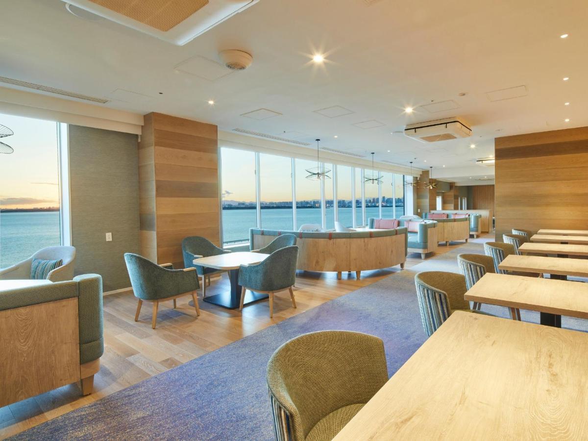 Grand Nikko Tokyo Bay Maihama Hotel Urayasu Exterior foto The photo shows a modern interior space, likely a dining or lounge area. It features large windows that offer a view of the water, allowing natural light to fill the room. The decor includes wooden walls and stylish, comfortable furniture, with sever