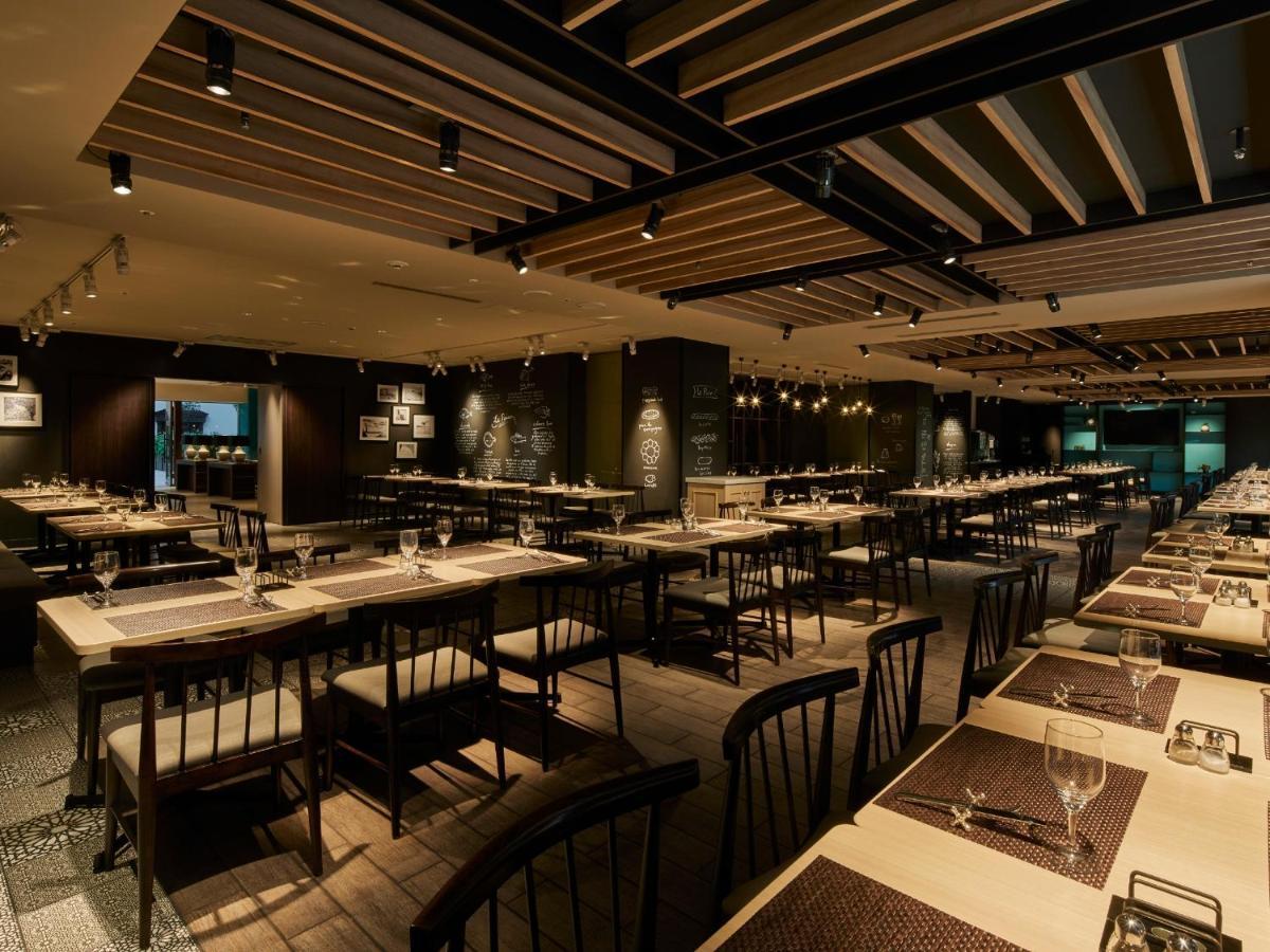 Grand Nikko Tokyo Bay Maihama Hotel Urayasu Exterior foto The photo shows the interior of a modern restaurant. The space features a spacious dining area with several long tables arranged in rows. Each table is set with dining utensils, plates, and glasses, indicating readiness for patrons. The lighting is s