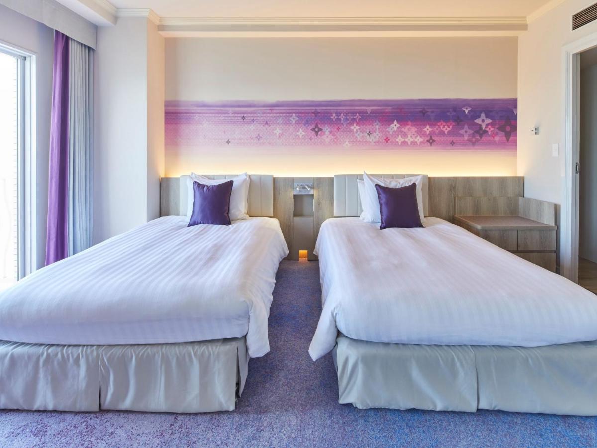 Grand Nikko Tokyo Bay Maihama Hotel Urayasu Exterior foto The photo shows a hotel room featuring two twin beds with white bedding and purple accent pillows. The beds are positioned next to each other, with a light-colored headboard. Behind the beds, there is a decorative wall with a gradient of purple hues.