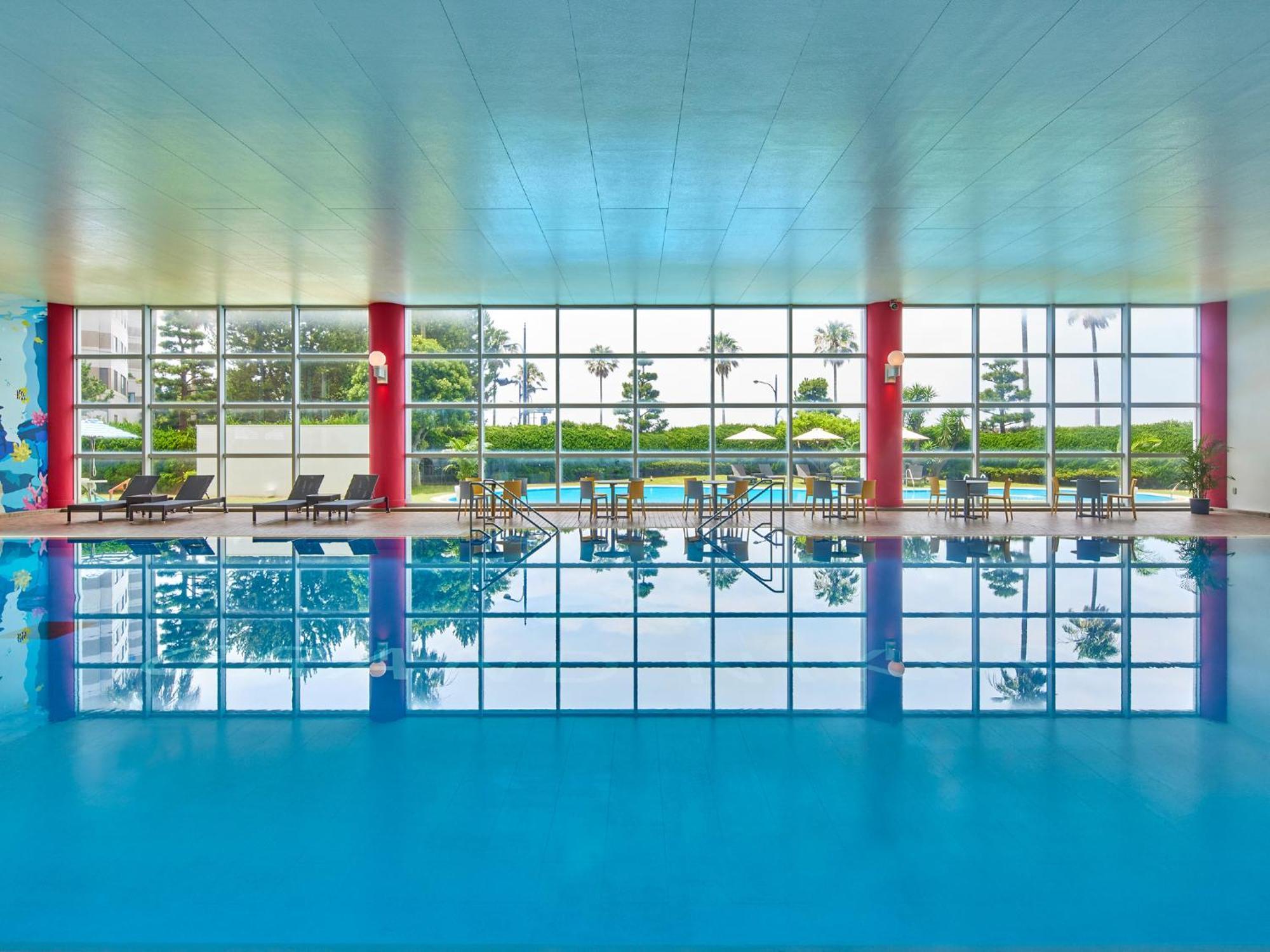 Grand Nikko Tokyo Bay Maihama Hotel Urayasu Exterior foto The photo shows an indoor swimming pool with bright blue water. The pool area is spacious, characterized by large windows that allow natural light to flood in, creating a vibrant atmosphere. The walls are painted in a soft color, with accents of red.